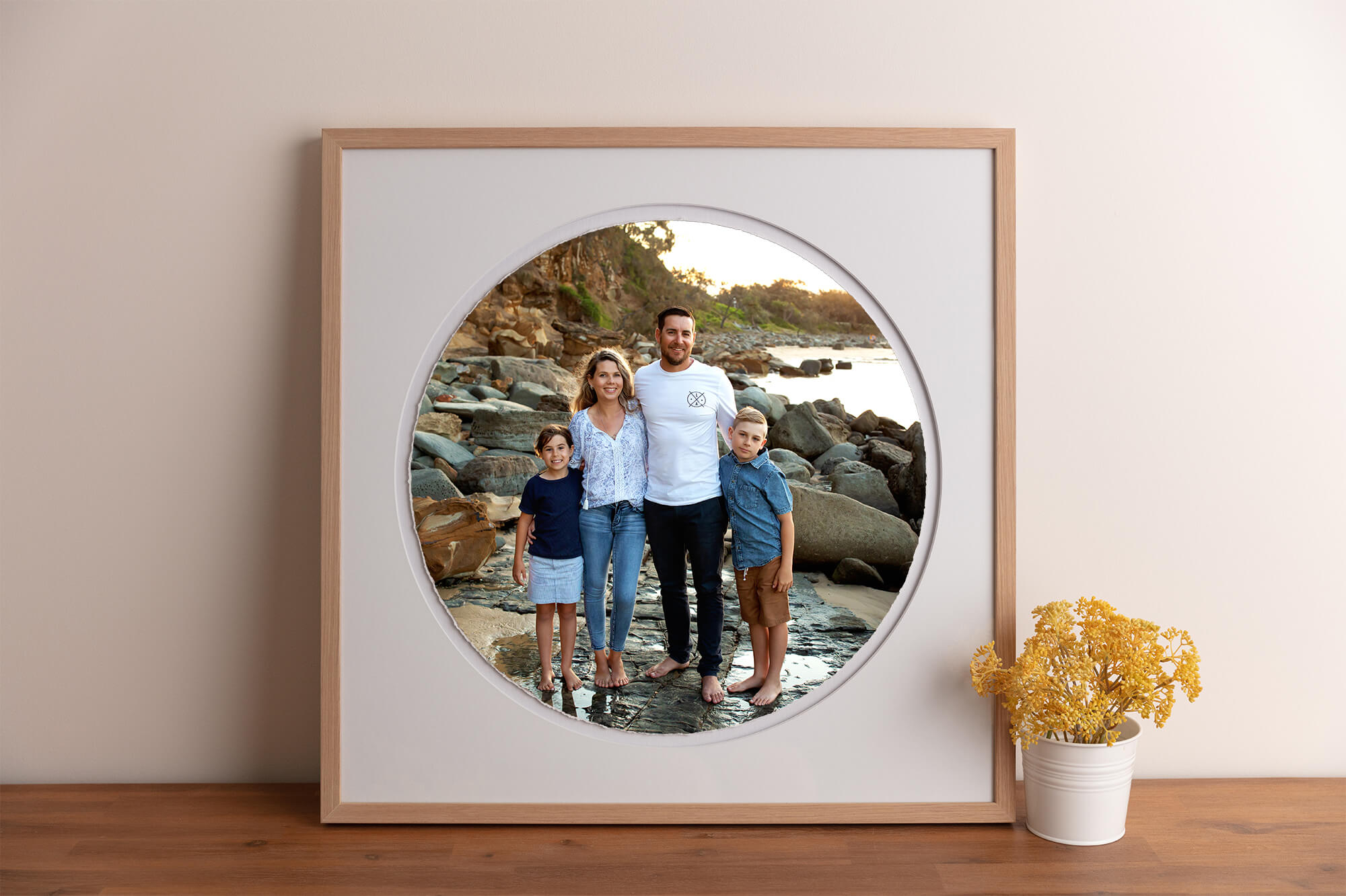 Family of four on a sunshine coast beach framed in a circle torn edge print with oak frame